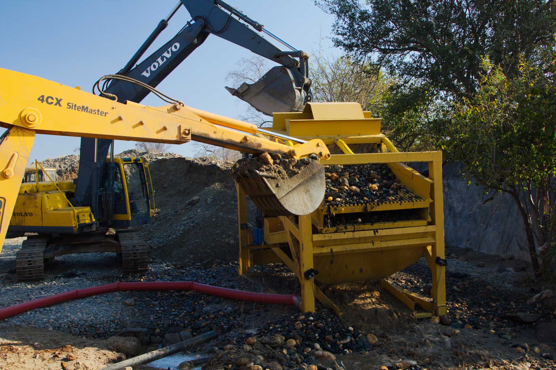 Excavator loading material into gold wash plant